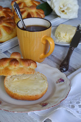 Buttermilk dinner buns served with butter, knife and jam on wooden background. Fresh baked brioche. Homemade baking. Breakfast