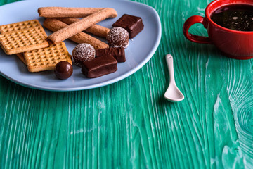 Shortbread cookies and chocolates on a btruzy plate, standing on a green wooden background.