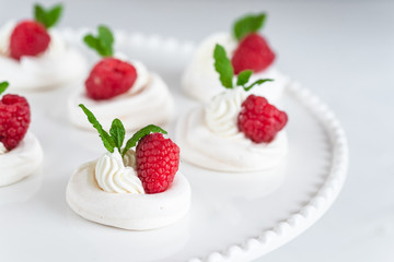 Mini Pavlova meringue with whipped cream and raspberries.