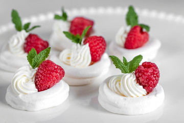Mini Pavlova meringue with whipped cream and raspberries.