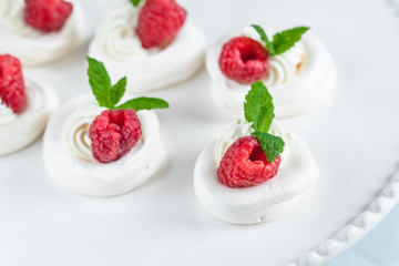 Mini Pavlova meringue with whipped cream and raspberries.
