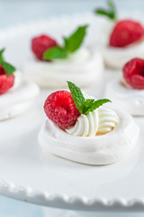 Mini Pavlova meringue with whipped cream and raspberries.