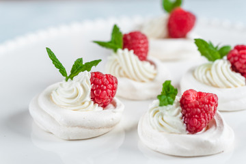 Mini Pavlova meringue with whipped cream and raspberries.