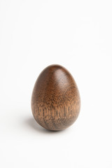 A perfectly standing oil-polished egg shape sculpture made from mahogany wood set on a white background.