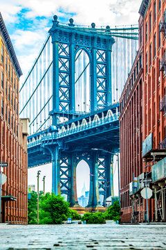 Fototapeta Manhattan Bridge between Manhattan and Brooklyn over East River seen from a narrow alley enclosed by two brick buildings on a sunny day in Washington street in Dumbo, Brooklyn, NYC