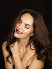 Naklejka premium Portrait of very attractive tender young dark haired woman with fashion makeup and wet skin effect on black background