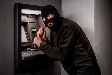 thief with crowbar opens the ATM.