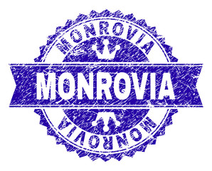 MONROVIA rosette seal imprint with distress style. Designed with round rosette, ribbon and small crowns. Blue vector rubber print of MONROVIA title with grunge style.