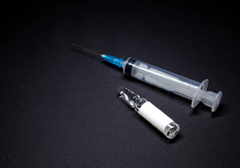 Syringe and ampoule on a black background. Injection preparation.