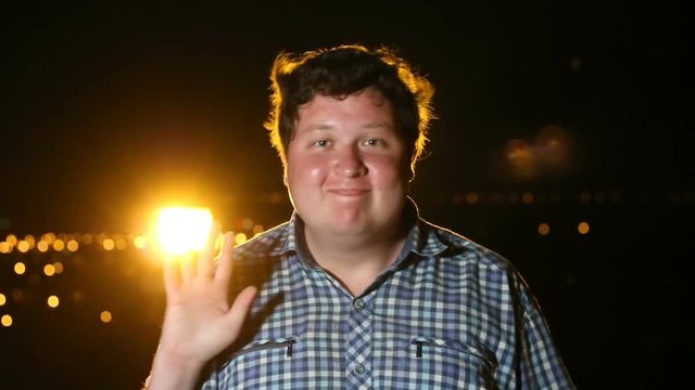 Man standing and waving hs hand at night outdoor, portrait