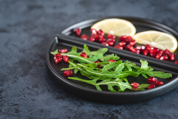 Fresh arugula, pomegranate seeds and lemon - ingredients for a low-calorie salad.