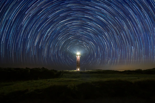 Lighthouse at night with star trails at the center