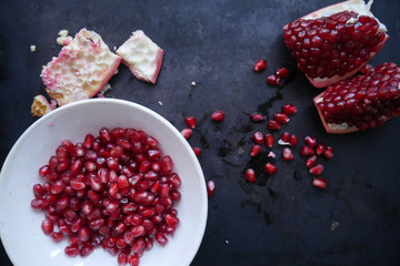 cut ripe pomegranate and pomegranate fruits, a plate with pomegranate fruits on a black background