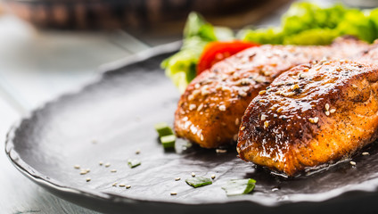 Delicious grilled roasted salmon fillets or steaks with sesame tomatoes and lettuce salad.