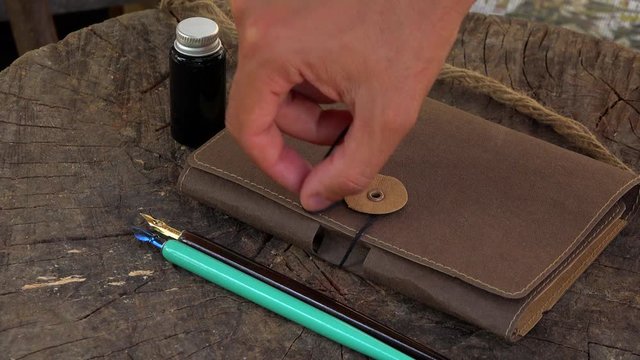 Closing and touching an agenda with thread, wood vintage fountan pen and ink pot bottle&nbsp;