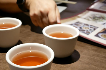 Close up of woman looking at menu and hot teas on table inside Chinese restaurant