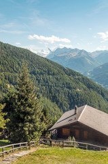 Wooden houses in the meadows of the Swiss Alps in the Saint Luc valley on a sunny day.