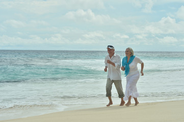 Portrait of happy elderly couple running on tropical beach