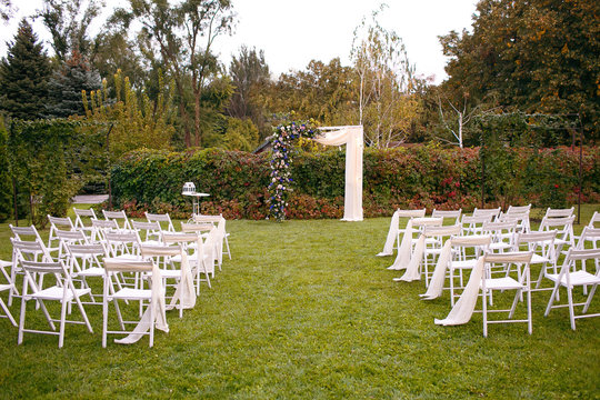 Wedding. Ceremony. Wedding arch. Wedding arch made of branches, flowers and greenery is on the green grass on the river bank