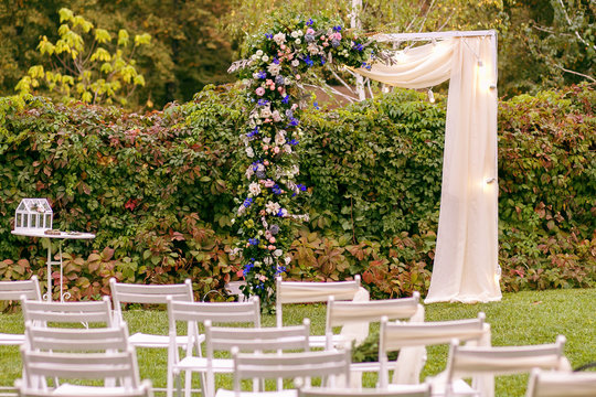 Wedding. Ceremony. Wedding arch. Wedding arch made of branches, flowers and greenery is on the green grass on the river bank
