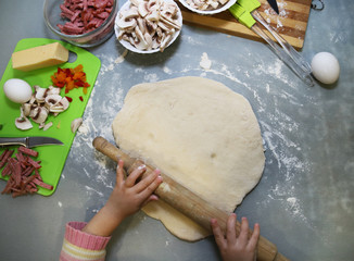 baby cooks pizza. view from above