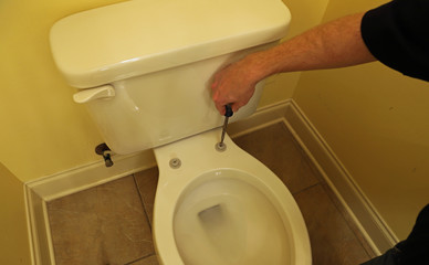 Plumber repairing broken toilet seat