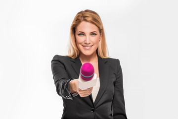 Attractive blonde TV presenter on white background holding a microphone and points to an object.