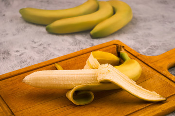 Ripe banana with white flesh on a wooden background. Tropical fruits.