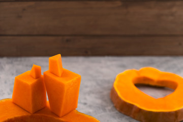 Stylized figures of a man and a woman carved from a pumpkin. Wooden background.