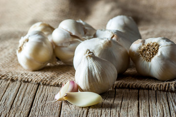 Ripe and raw garlic wooden table with burlap sack, alternative medicine, organic cleaner. Garlics background