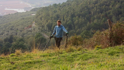 young man in the mountains looks for buried and forgotten treasures with his metal detector.