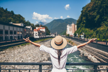 Fototapeta premium Happy girl at hat on the embankment of a mountain river in a European city.