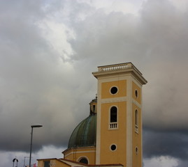 high tower or bell tower of a church. ocher or cream color. the sky is dark and cloudy