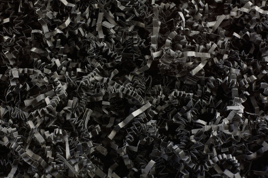 Close up of crinkled shredded black paper box filler for shipping fragile items to prevent damage and breakage