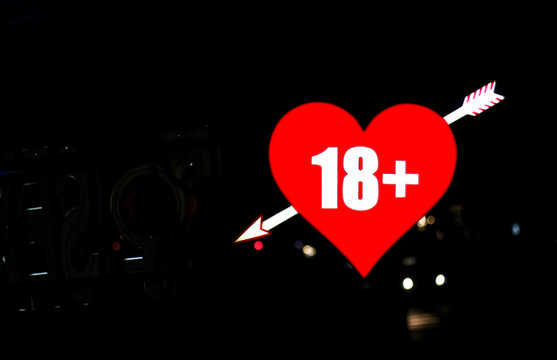 Red neon heart with arrow over night background 18+.  space for your text