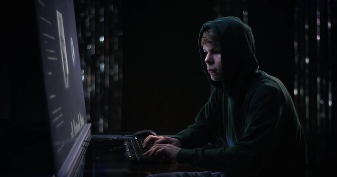 Hooded teenage boy hacking desperately