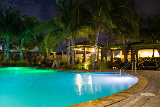 Beautiful Resort Hotel Pool At Night With Lights And Palm Trees In Tropical Location