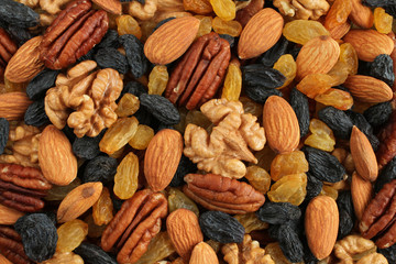 Food background - big peeled almonds,  peeled pecan nuts, big dark blue raisins and yellow raisins situated arbitrarily