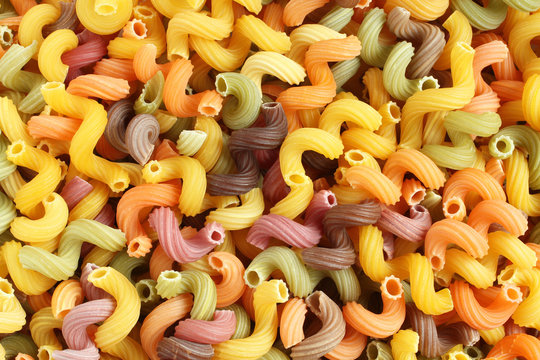 Food background - uncooked colorful Cavatappi (Celentani) durum wheat pasta with beetroot, spinach, carrot and tomato