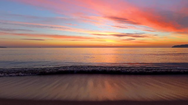 Beautiful tropical sunrise on the beach. Waves washing the sand on the bay.