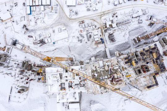 aerial top view of new city residential area under development, building machinery working under snow