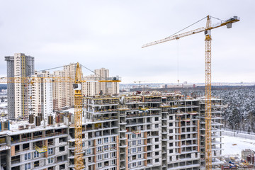 aerial panoramic view of construction city site in winter. yellow tower cranes building new...