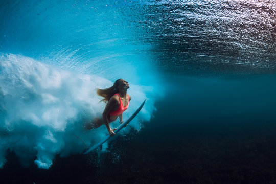Attractive surfer woman dive underwater with big wave.