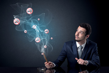 Businessman smoking with floating no smoking signs beside his head.