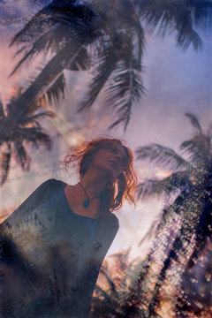 Beautiful young boho woman on tropical background at sunset