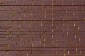 Low angle view of a purple brown brick wall abstract background with raking stretcher bond brickwork pattern
