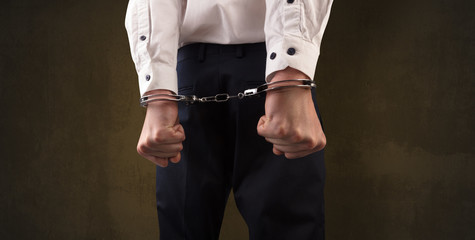 Close now arrested men hand with dark background and handcuffs
