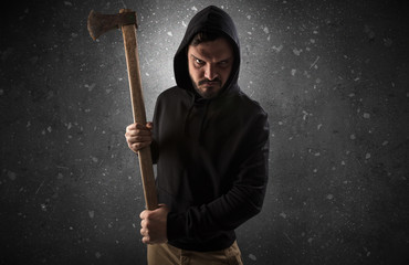 Masked armed villain in empty dark room with gun ax chainsaw mallet wrench

