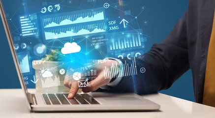 Businessman hand typing on laptop with reports and graphs concept around
