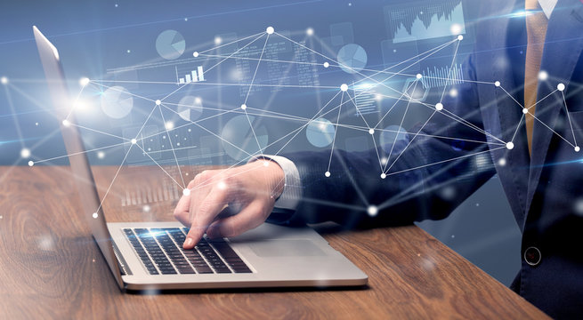 Businessman typing on laptop with linked reports charts grapghs around
